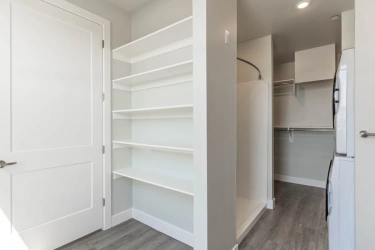 Kenosha apartments for rent - image - Modern apartment closet with sleek built-in shelves and a washing machine, offering efficient storage solutions.