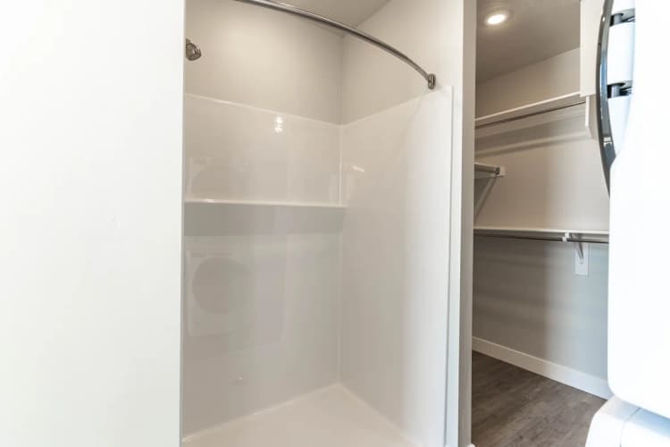 Kenosha apartments for rent - image - Modern bathroom with sleek shower stall and adjacent spacious walk-in closet featuring ample shelving.