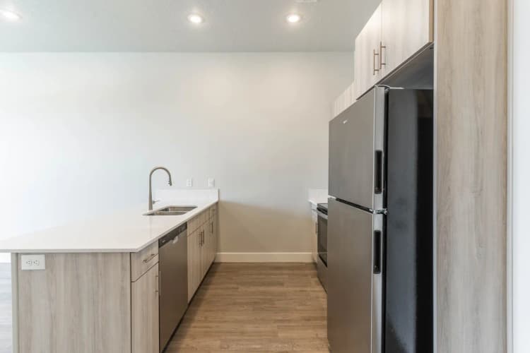 Kenosha apartments for rent - image - Sleek and modern kitchen with stainless steel appliances, elegant wooden cabinetry, and a spacious quartz countertop.