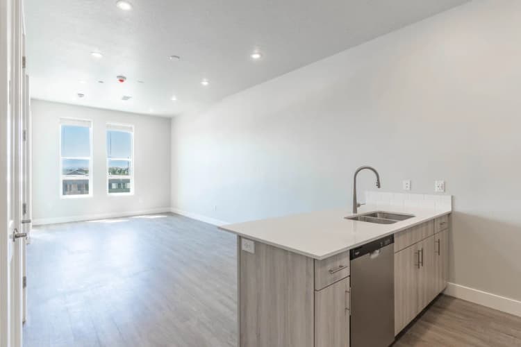 Kenosha apartments for rent - image - Bright open-concept living space with sleek modern kitchen, expansive windows, and elegant wood flooring.