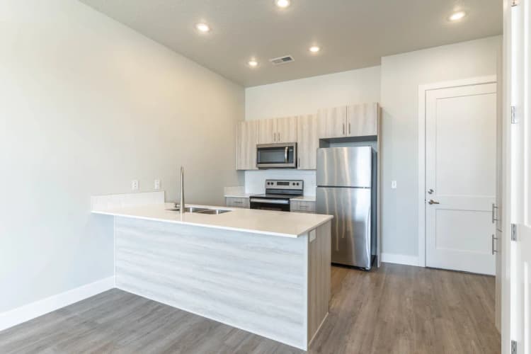 Kenosha apartments for rent - image - Modern kitchen featuring sleek stainless steel appliances, stylish cabinetry, and a spacious island with a built-in sink.