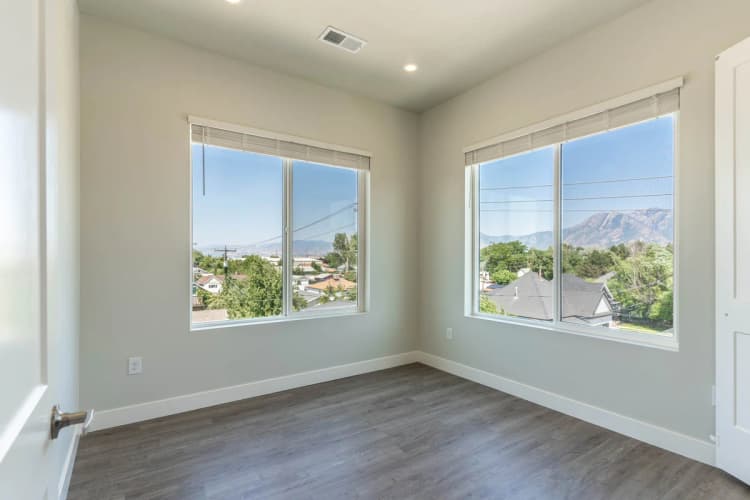 Kenosha apartments for rent - image - Bright room with large windows showcasing a stunning mountain and suburban view, featuring modern wood flooring and soft neutral walls.