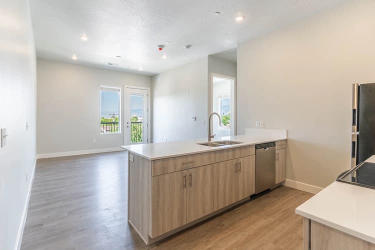 Kenosha apartments for rent - image - Modern open-concept kitchen with sleek appliances and a sunlit living area featuring expansive windows and a scenic view.