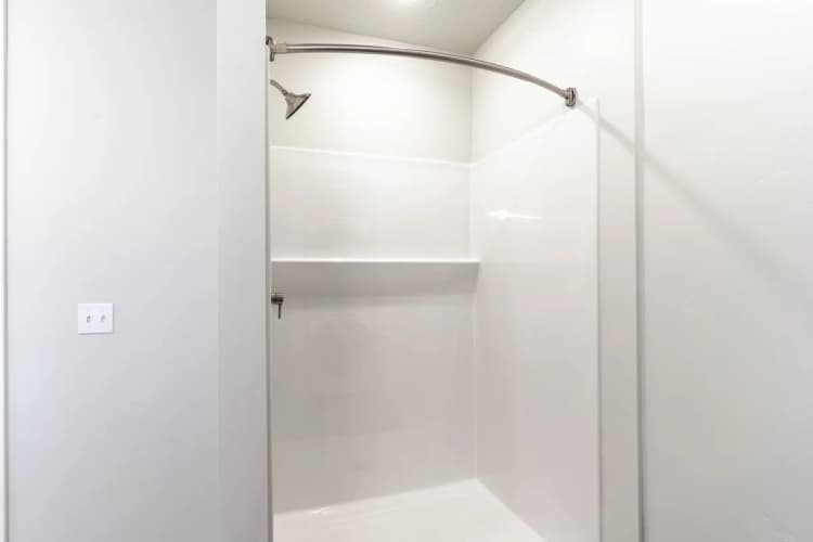 Kenosha apartments for rent - image - Modern bathroom with sleek shower space featuring a curved curtain rod and bright white walls.