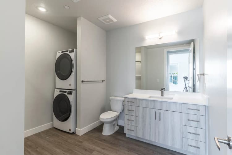 Kenosha apartments for rent - image - Modern bathroom with sleek vanity, a mirror, and an integrated laundry area showcasing stacked washer and dryer.