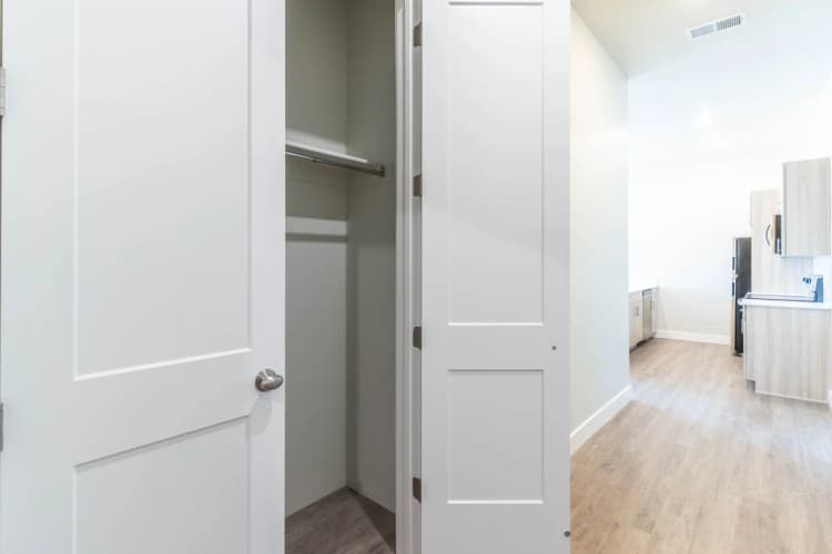 Kenosha apartments for rent - image - Modern kitchen with stylish cabinetry and open layout, enhanced by a spacious closet with white paneled doors, offering seamless storage solutions.