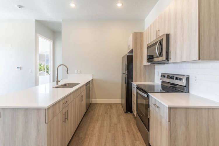 Kenosha apartments for rent - image - Modern kitchen design featuring sleek wood cabinetry, stainless steel appliances, and a spacious island with elegant countertops.