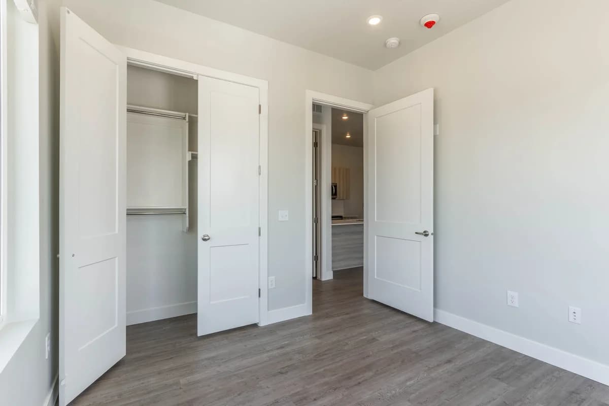 Kenosha apartments for rent - image - Bright, modern room with open closet space and sleek hardwood flooring, leading to a stylish kitchen area.